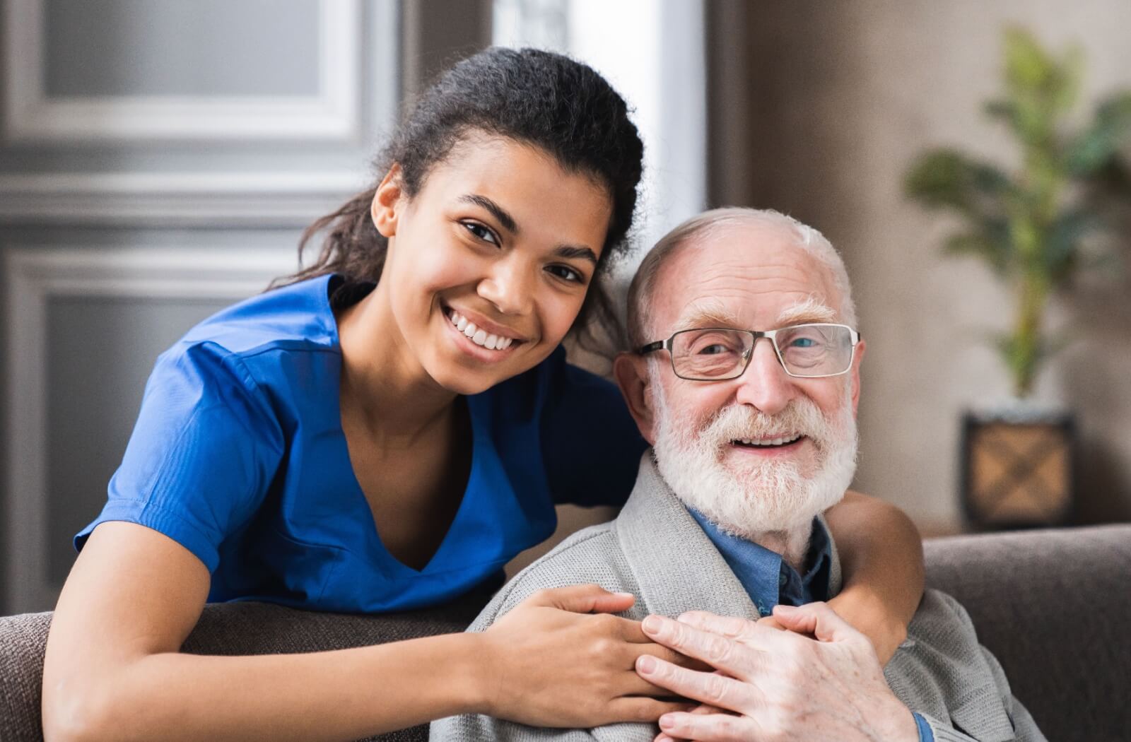 An assisted living staff hugging a resident from behind