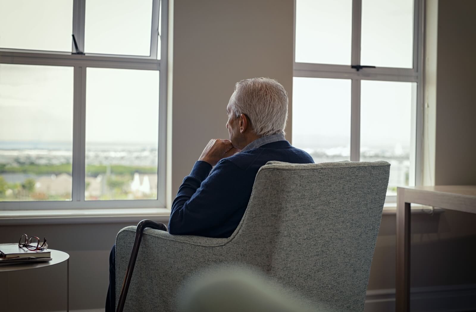 A senior sits alone in their apartment, staring out the window and wishing they had someone to connect with